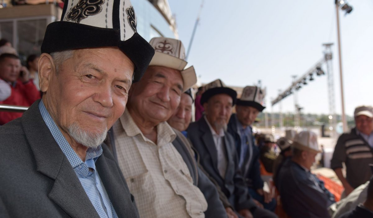 Moira O’Shea, Kyrgyzstan, 2018, This photo was taken during the World Nomadic Games in CholponAta, Kyrgyzstan, 2018. Attending every match of Kok-boru, I became
friendly with some of the fans who also watched every match, like this
group, some of whom had come from Jalal-Abad together. Sitting
with them was an education in the skills and characteristics one needs
to become a good Kok-boru player, as well as an opportunity to hear
stories about their own adventures, and sometimes misadventures,
when playing the game.