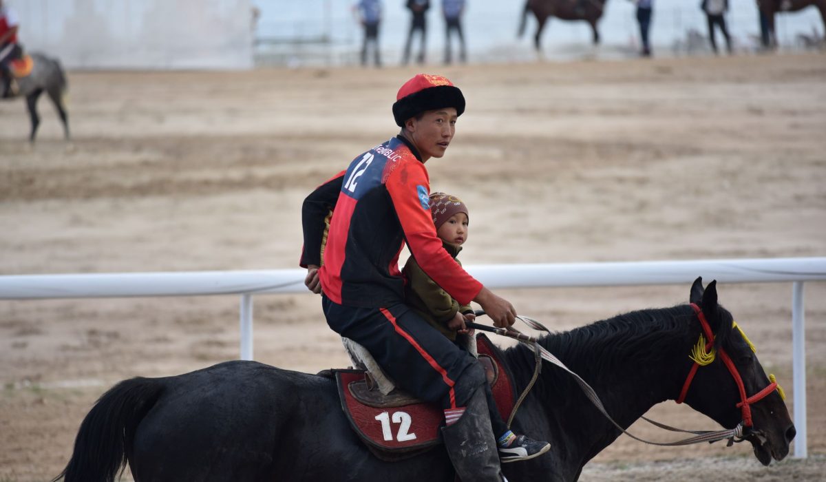 Moira O’Shea, Kyrgyzstan, 2018, Research on the history and contemporary form of Kok-boru has led
to conversations about the origin of the game, about which country’s
rules to use in international games, and the mutual understanding
between a rider and his horse. One idea that has stood out, however,
is the idea that Kok-boru is something that is in the blood and which
is not explicitly taught but rather demonstrated. To me, this picture,
taken after Kyrgyzstan won the final match during the World Nomadic
Games in 2018, illustrates the sharing of knowledge of the game from one generation to the next. Cholpon-Ata, Kyrgyzstan.