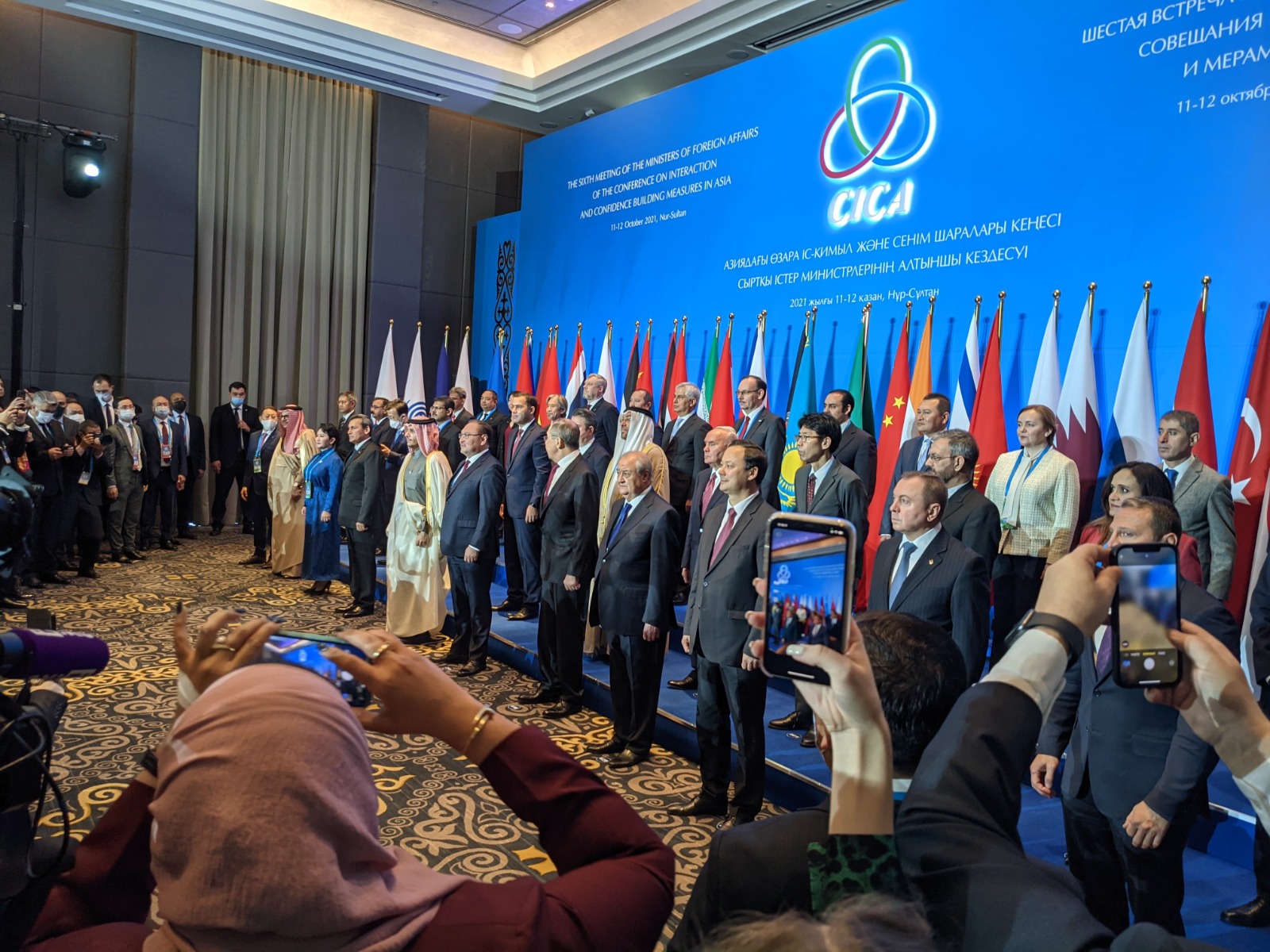 Image of multiple diplomats mostly males in suites in front of flags at CICA summit in Astana, 2021