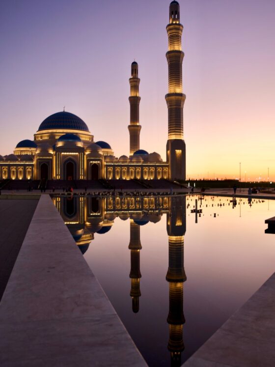 a mosque at dusk time reflecting in water