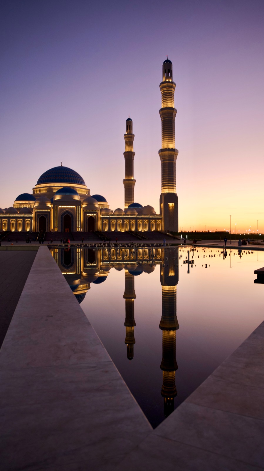 a mosque at dusk time reflecting in water