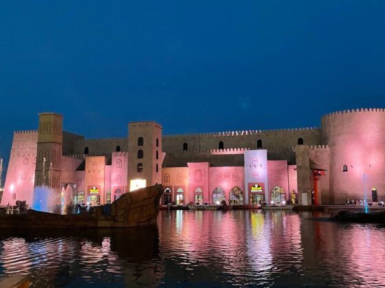 A real size replica of an ancient fort wall illuminated at night and reflected in the artificial pond.