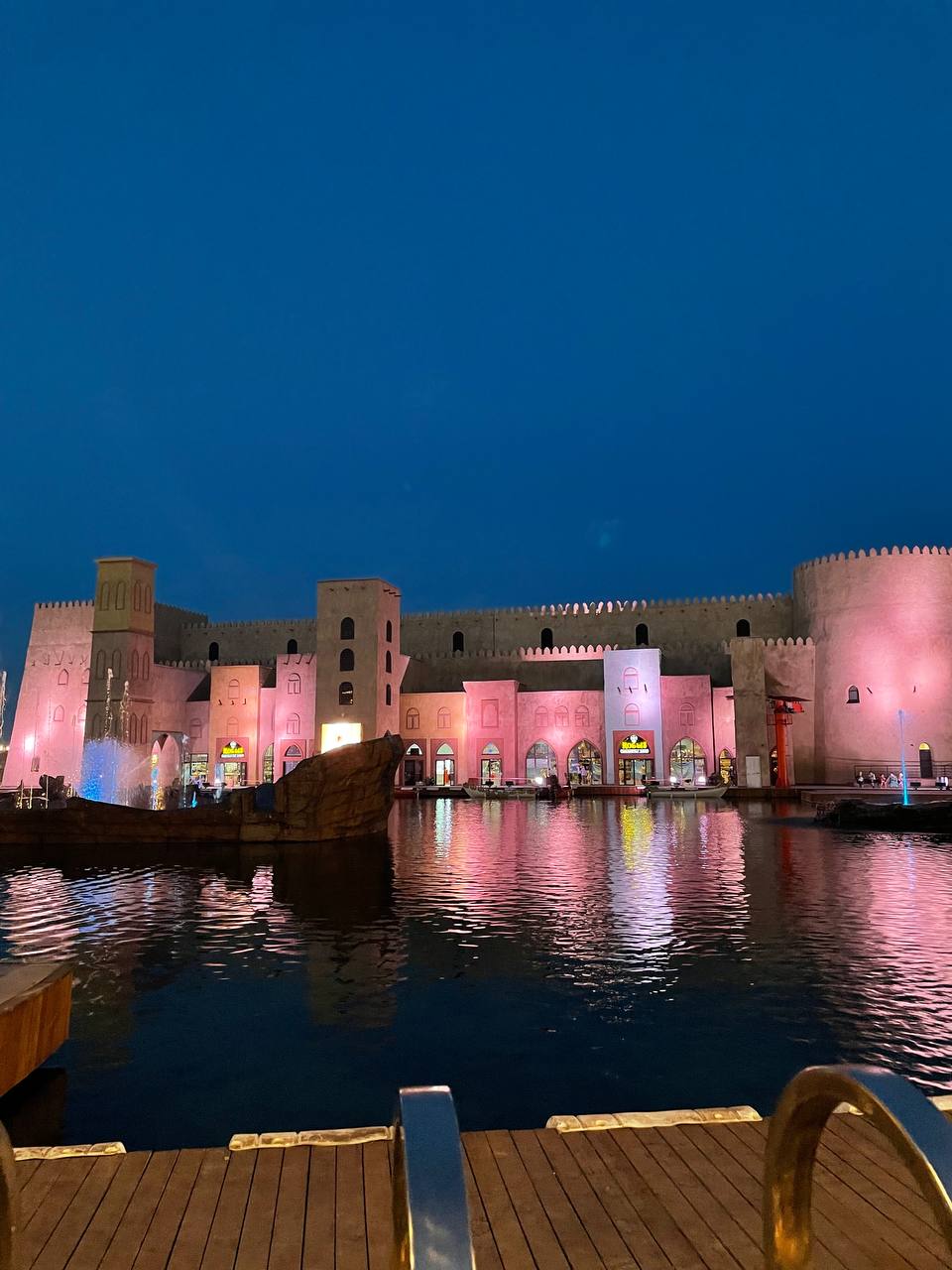 A real size replica of an ancient fort wall illuminated at night and reflected in the artificial pond.